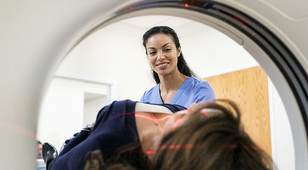 Healthcare professional with a patient in an MRI machine.