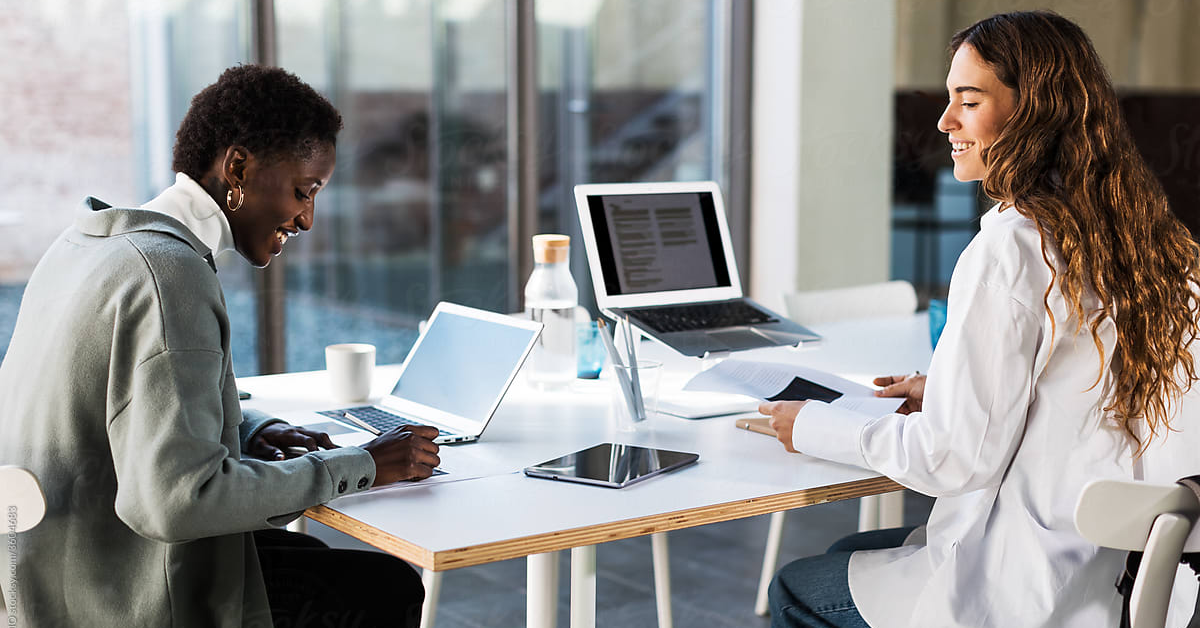 Two clinical trial coordinators at a table with computers and ipads